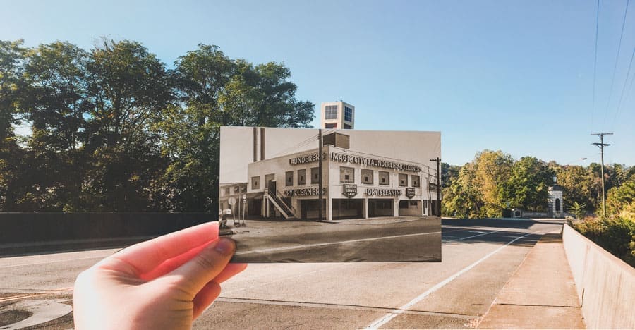 A hand holds a vintage photo of the Magic City Laundry & Cleaners building over a modern street.