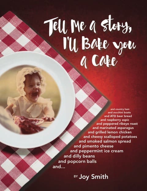 A smiling toddler in a white bonnet, face smeared with red jam, sits behind a white plate on a red gingham cloth.